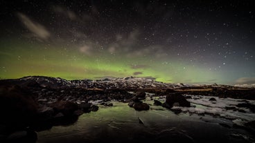 The nothern lights glow in the sky above Iceland's mountainous landscape.