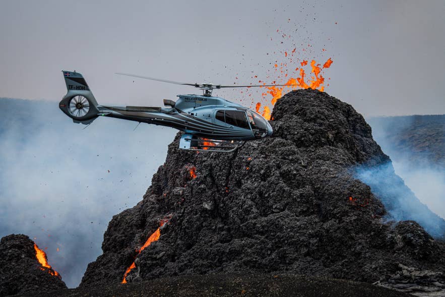 Helicopter hovering beside an erupting volcanic cone in Iceland