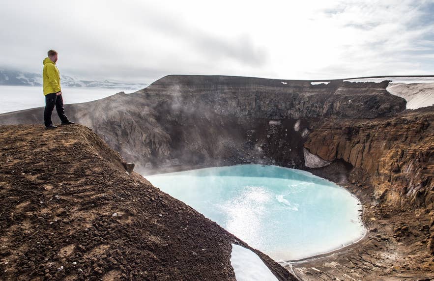 Ein Reisender am Kratersee Viti in Askja im Hochland von Island, einer vulkanischen Stätte, die oft im Rahmen von Touren zum Myvatn-See besucht wird.