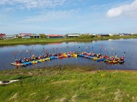 Een groep kajakkers poseert op het water en heft hun roeispanen op voor een foto