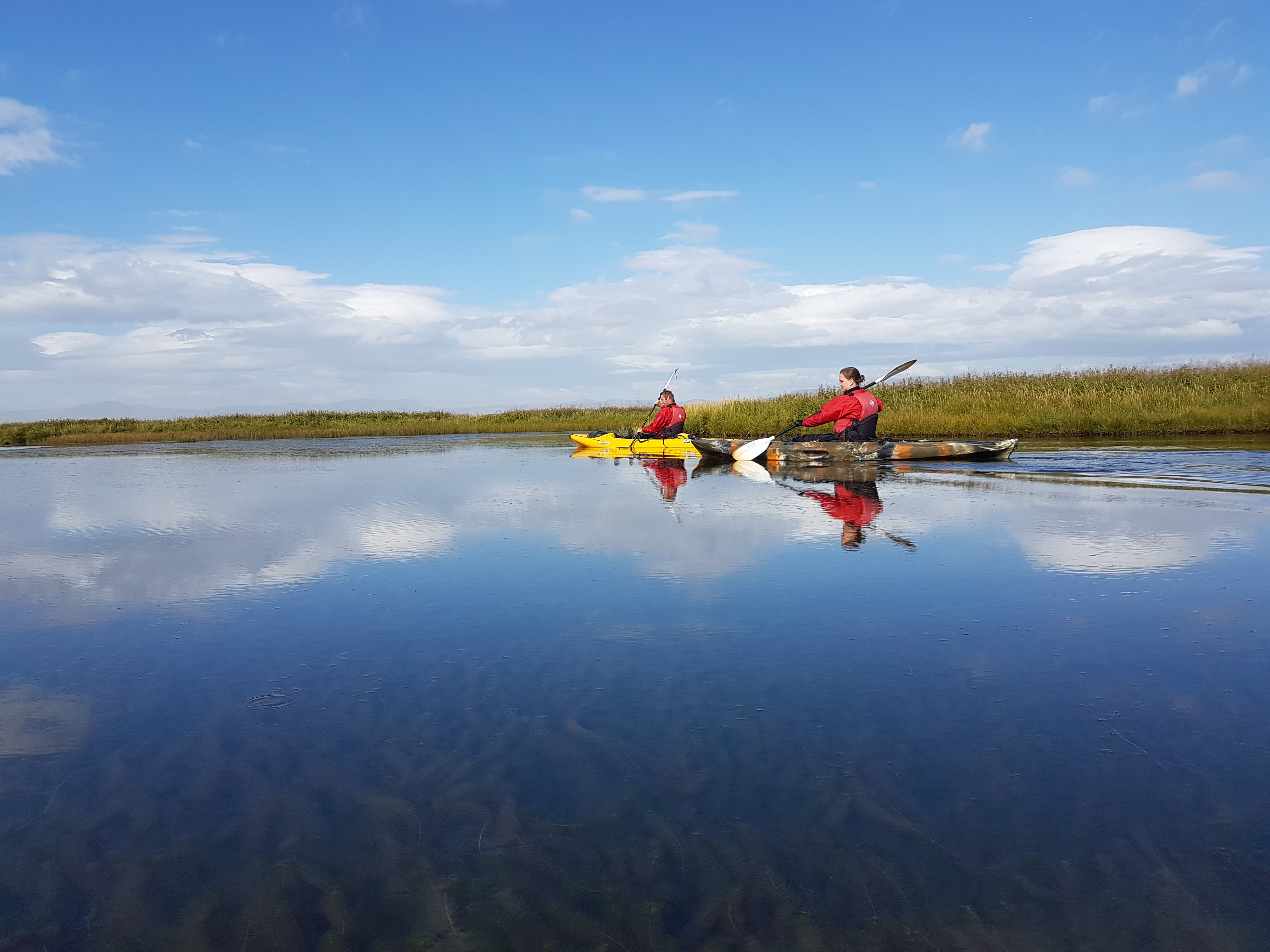 Dos aventureros haciendo kayak en un tranquilo día de verano en los ríos del sur de Islandia.