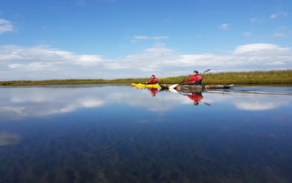 Dos aventureros haciendo kayak en un tranquilo día de verano en los ríos del sur de Islandia.