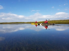 Två äventyrare som paddlar kajak på en lugn sommardag på floderna på södra Island.