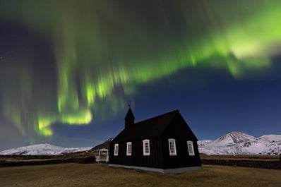 Northern Lights dance across the sky behind the charming black church on the Snæfellsnes Peninsula.