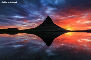 Góra Kirkjufell na półwyspie Snæfellsnes odbijająca się w spokojnej tafli wody.