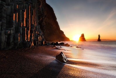 Maestose colonne di basalto e faraglioni sull’iconica spiaggia di sabbia nera di Reynisfjara.