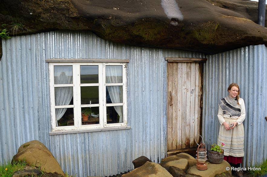 Une femme pose près d’une grotte artificielle, nichée au pied de falaises de lave spectaculaires dans la région de Laugarvatn.