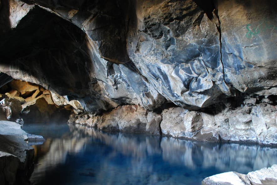 Layered volcanic rock reflects in the clear pool inside Grjotagja lava cave in North Iceland. Layered volcanic rock reflects in the clear pool inside Grjotagja lava cave in North Iceland.