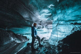 En reisende utforsker en isgrotte på Sør-Island