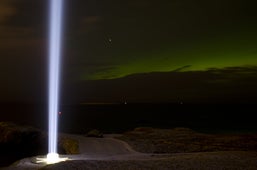 Northern Lights dancing alongside the beam of the Imagine Peace Tower.