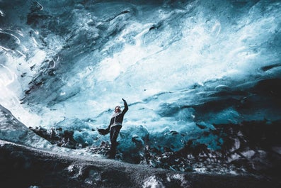 A man stands inside a beautiful ice cave in Iceland.