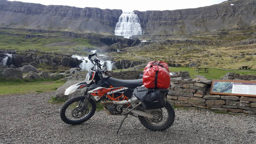 Loaded KTM enduro motorcycle parked in front of Dynjandi Waterfall in the Westfjords