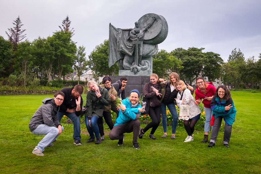 Un grupo de personas posa ante una escultura de Einar Jónsson en el parque de Hljomskalagardur, que representa a un guerrero matando a un dragón.