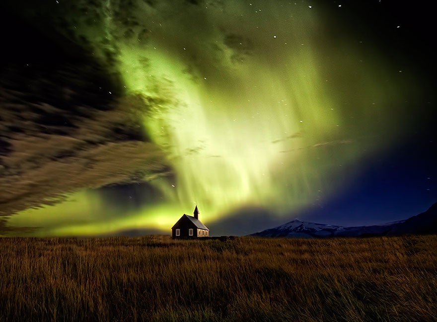 La iglesia de Budir, al oeste de Islandia, bajo un resplandor de auroras boreales verdes.