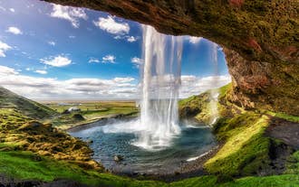 Derrière le rideau d'eau de la cascade de Seljalandsfoss, sur la côte sud de l'Islande.