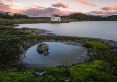 Ein altes Haus am Ufer des Flusses Lagarfljót im Osten Islands an einem ruhigen Sommerabend.