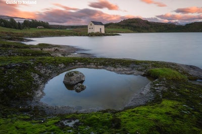 Et gammelt hus står ved bredden av elven Lagarfljot på Øst-Island en fredelig sommerkveld.