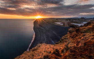 Solen går ned over den endeløse sorte sandstrand på Islands sydkyst.