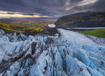 Green flora, white glacier and dark mountains in Skaftafell nature reserve.