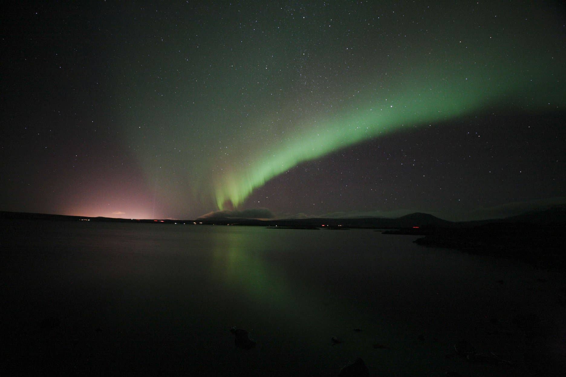 A blaze of green and pink northern lights forming in the night sky.
