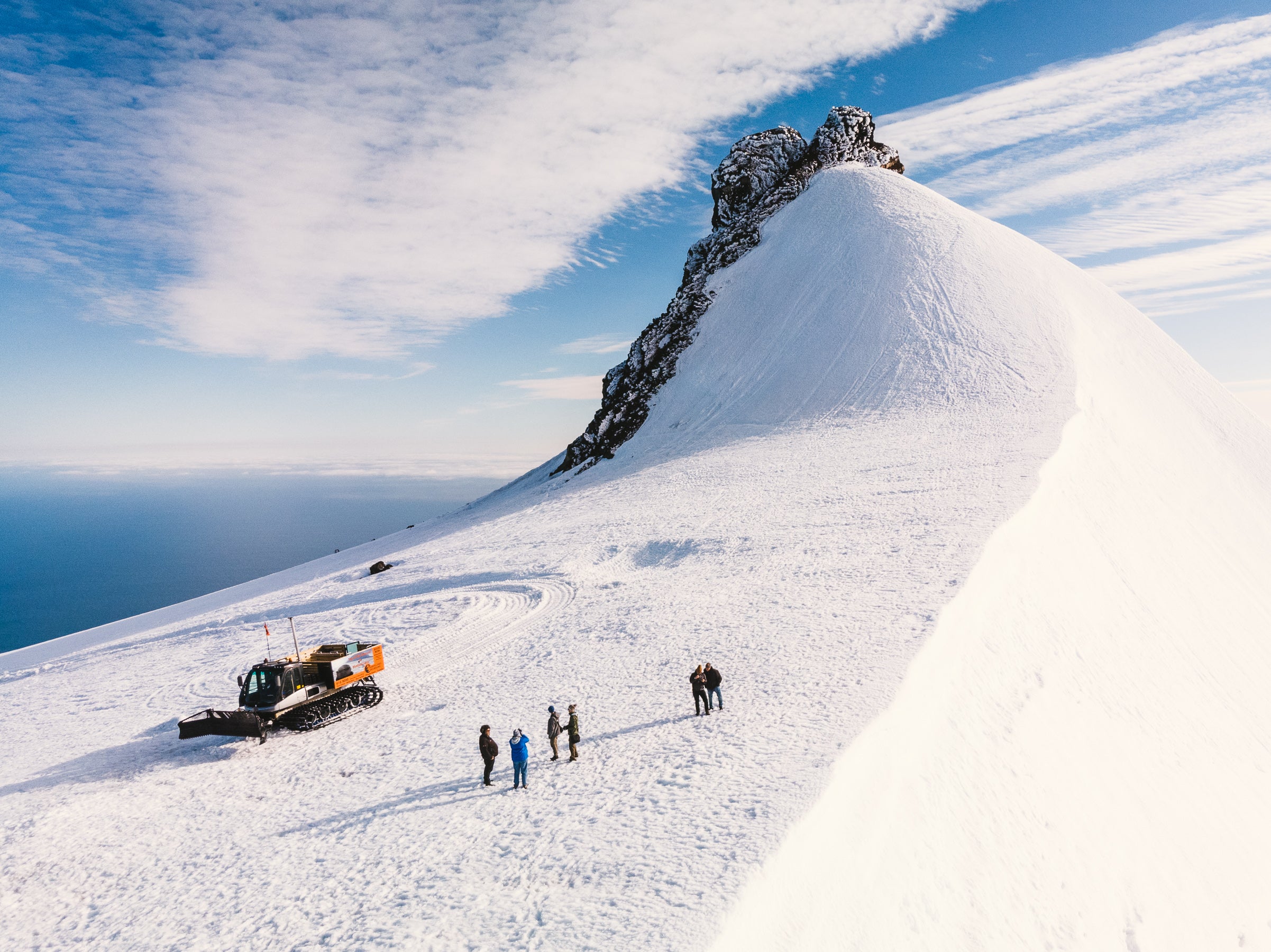 En grupp resenärer på snövessla beundrar omgivningen på en glaciär