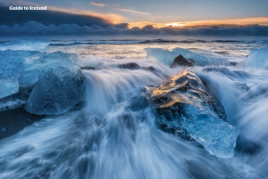 Ice chunks on Diamond Beach at sunrise, with ocean waves and dramatic sky near Jökulsárlón glacier lagoon in Iceland. Ice chunks on Diamond Beach at sunrise, with ocean waves and dramatic sky near Jökulsárlón glacier lagoon in Iceland.