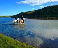 Horse riders crossing a river in South Iceland.