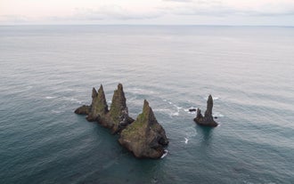 De rotsformaties van Reynisdrangar staan uitdagend in zee bij het strand van Reynisfjara.