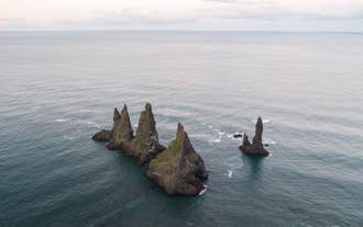 Reynisdrangar-steinene står trassig ut mot havet ved Reynisfjara-stranden.