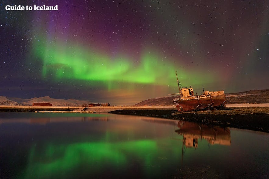 Aurores Boréales apparaissant au-dessus d'un bateau dans les Fjords de l'Ouest en Islande.