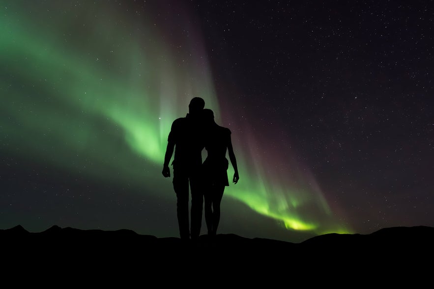 A young couple look to the Northern Lights.