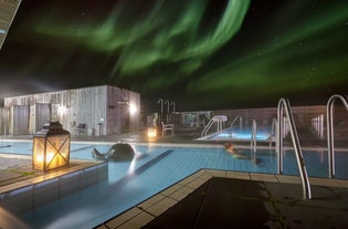 Two of the pools and the sauna at Fontana Geothermal Baths with the northern lights seen overhead.