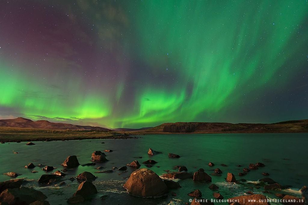 Das Grün der Polarlichter schimmert im See darunter