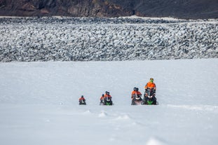 People riding snowmobiles across the vast Myrdalsjokull glacier.