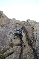 A person scales a rock face on a climbing tour in Iceland.