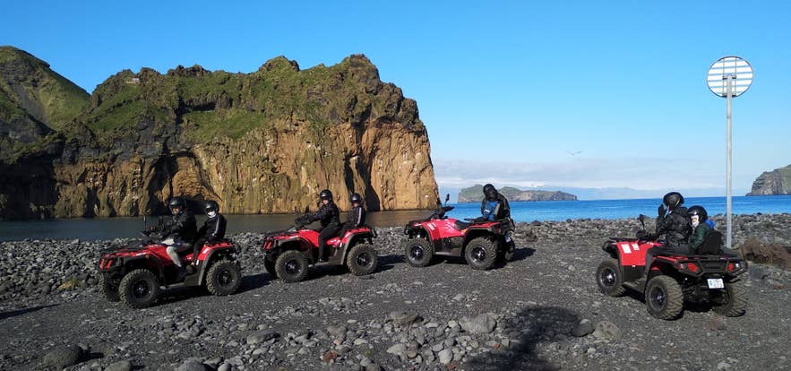 冰岛南部赫马岛上，乘坐全地形车的游客探索黑沙海岸，周围是火山悬崖和海景。