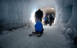 Child riding a sled inside the Langjokull Ice Tunnel in Iceland during a guided glacier cave tour.