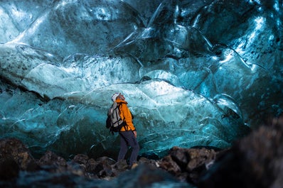 A hiker explores the ice formations of an ice cave in Vatnajokull.