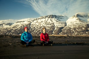 Two woman sitting at the ground while doing yoga in the vastness of Breiddalur valley, near Breiddalsvik.