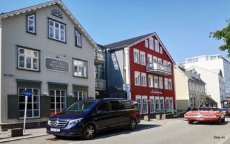 Sininen V-sarjan Mercedes pysäköitynä värikkäiden talojen eteen Reykjavíkissa.