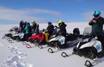 A row of snowmobile riders prepare to ride across the Langjokull glacier.