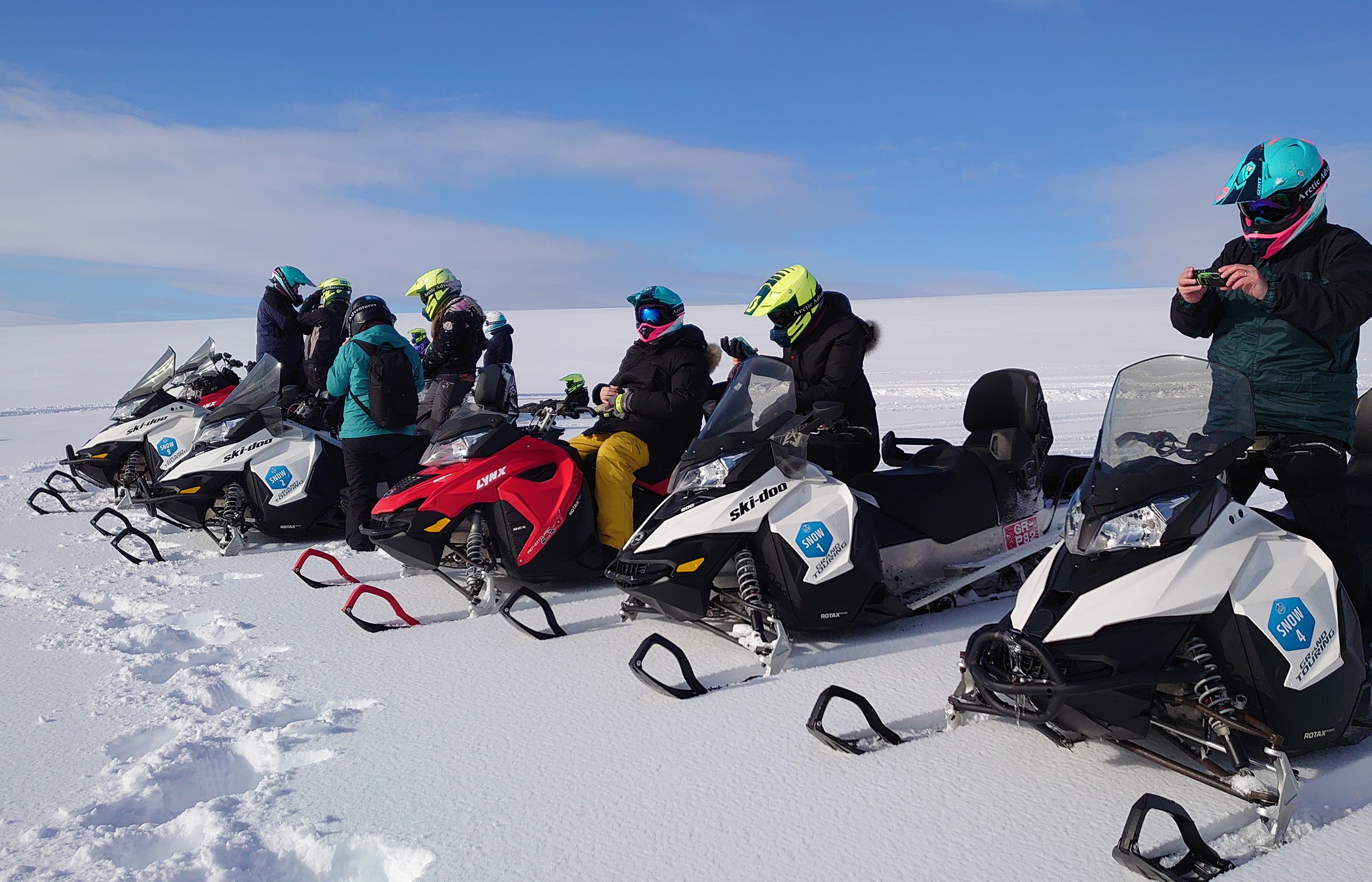 A row of snowmobile riders prepare to ride across the Langjokull glacier.