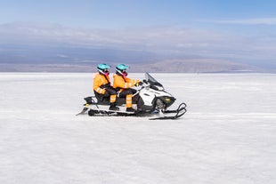 Two adventurers explore the snowy landscapes of Langjokull on a snowmobile.