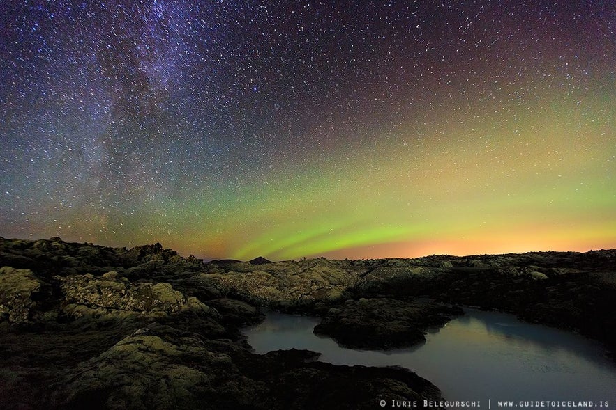 Una notte particolarmente stellata con l'aurora boreale che appare come un'alba cosmica all'orizzonte.