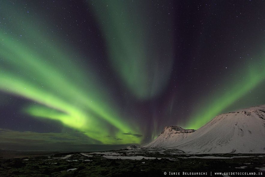 Aurora boreale verde brillante con sfumature rosse e rosa