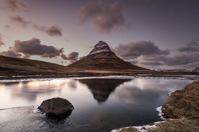 Góra Kirkjufell z widokiem na spokojne jezioro na półwyspie Snaefellsnes.