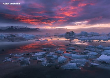 Jökulsárlón gletsjerlagune bij zonsondergang, waarbij het ijs zachtjes de laatste gouden en roze stralen van de zomerzon weerkaatst.