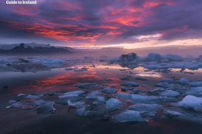 Jokulsarlon i solnedgang, med isen som forsiktig reflekterer sommersolens siste gylne og rosa stråler.