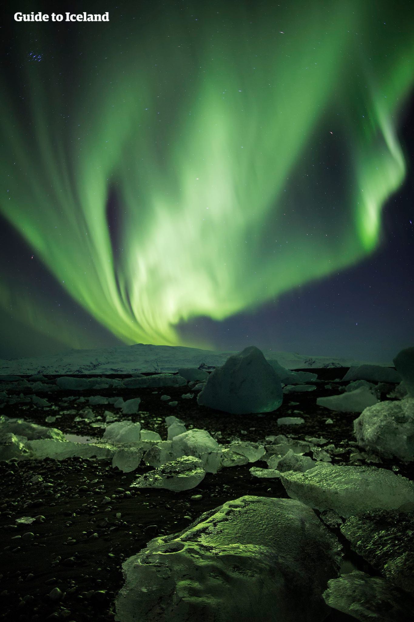The auroras on the Diamond Beach make the icebergs glow green.