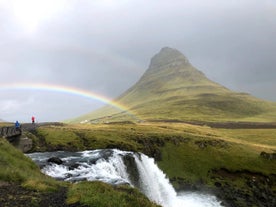 A rainbow forms in front of the Kirkjufell mountain.